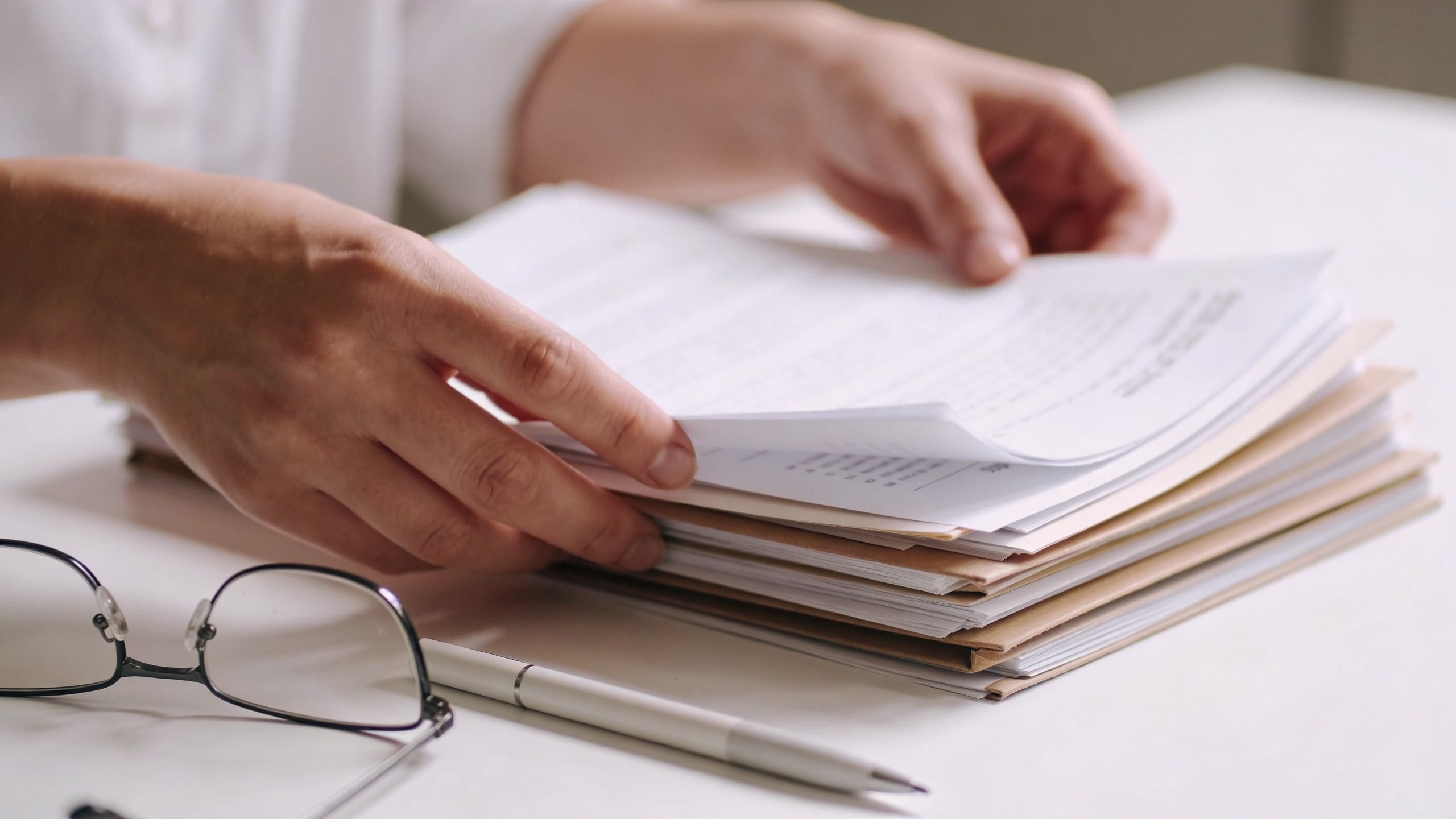 A professional reviewing a stack of important legal documents and paperwork on a desk in an office.